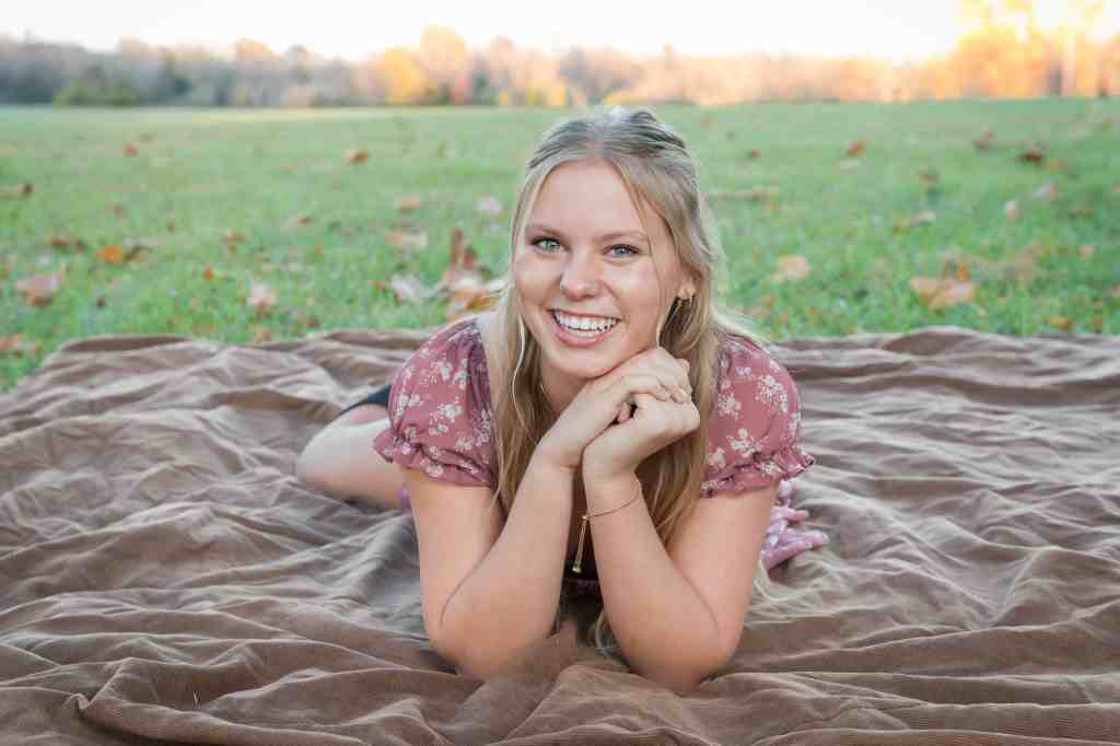 Case Studios Photography Senior girl posed on a blanket among green grass and fall leaves