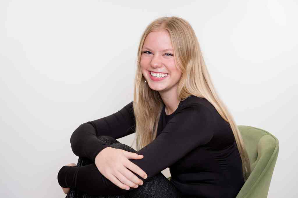 Case Studios Photography Senior girl sitting in a green chair against a white wall