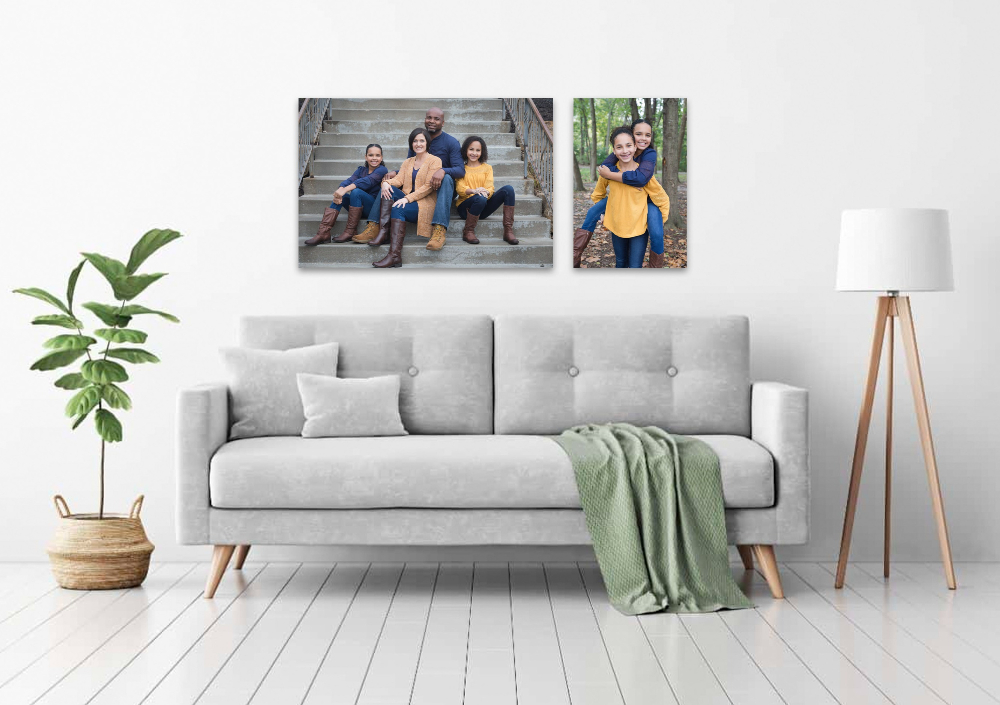 Family portraits above a gray couch in a minimalist living room. One photo shows four people on steps. The other, two kids in a forest.