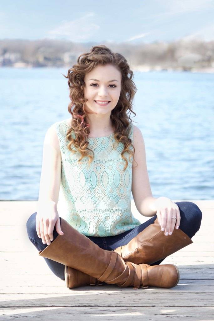 senior girl sitting on a dock next to a lake