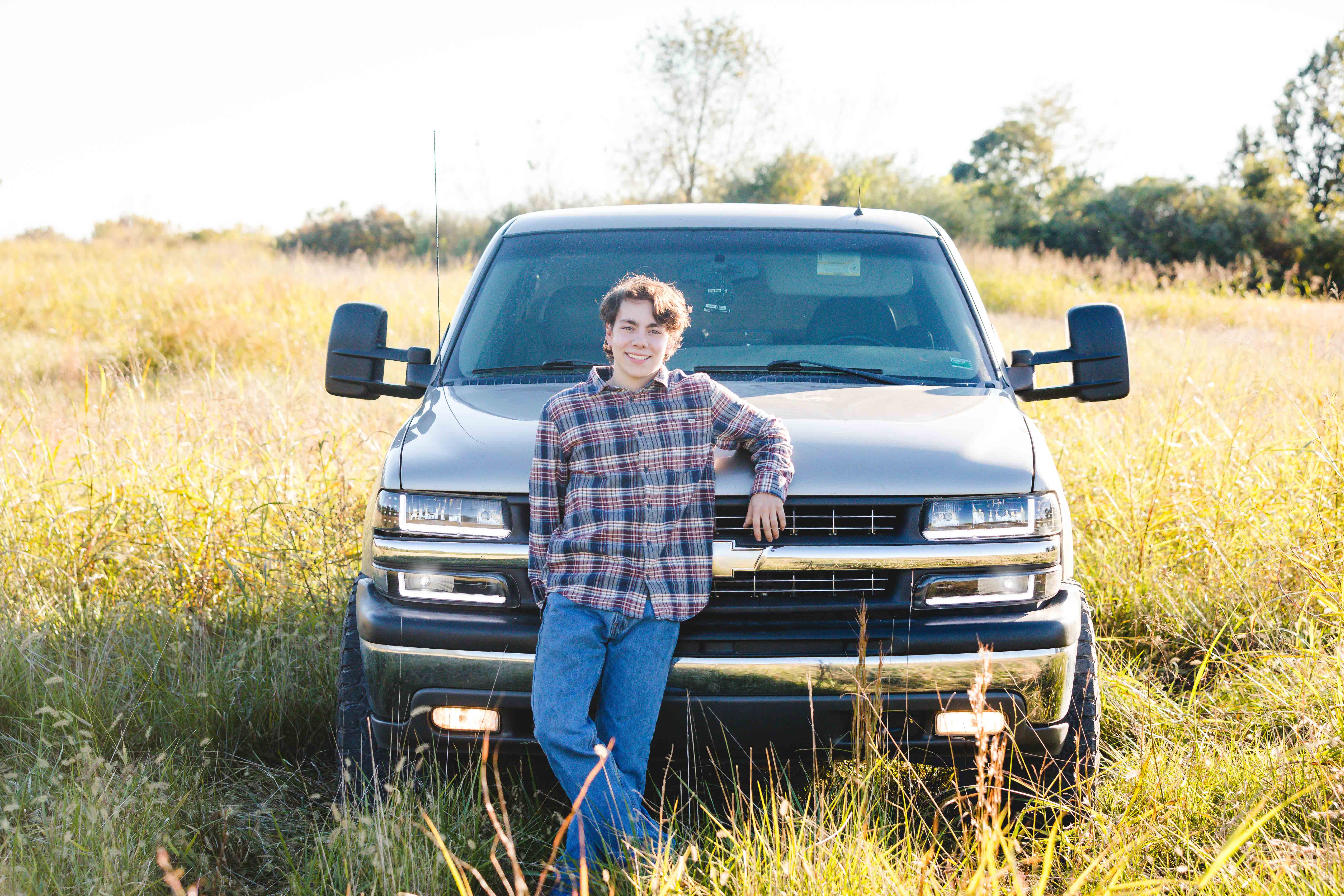 high school senior guy photographed with his truck in a tall grass field in Blue Springs Mo during a senior session photographed by Case Studios Photography